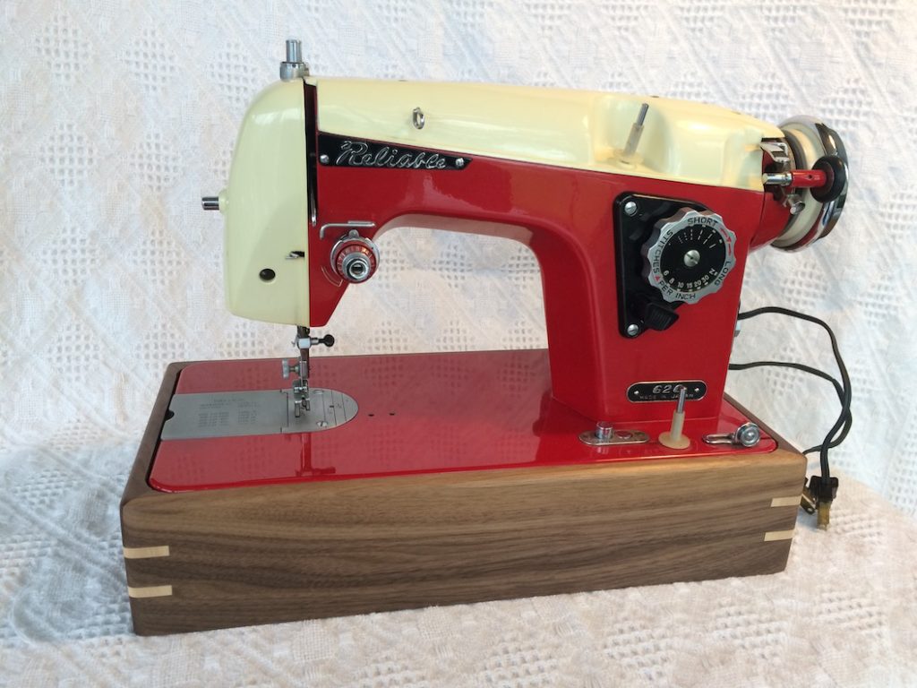 Photo of an antique sewing machine displayed in a walnut sewing machine stand