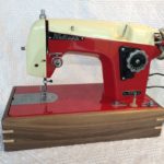 Photo of an antique sewing machine displayed in a walnut sewing machine stand